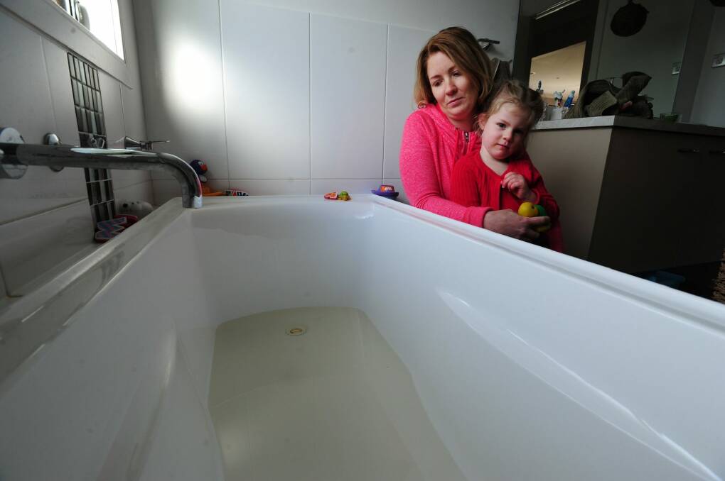 Dimity Smith, of Yass, and her daughter Violet, 4, with their bath tub that shows the discolouration of Yass water.  Photo: Melissa Adams 