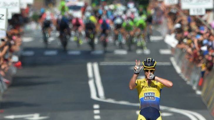 Michael Rogers of Canberra claims the stage victory as the peloton looms behind him. Photo: AP