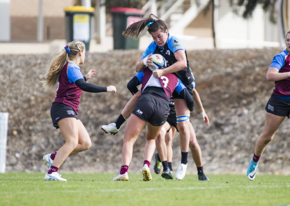 UC's Samantha Wood gets tackled by Queenslands Pleuni Kievit. Photo: Elesa Kurtz