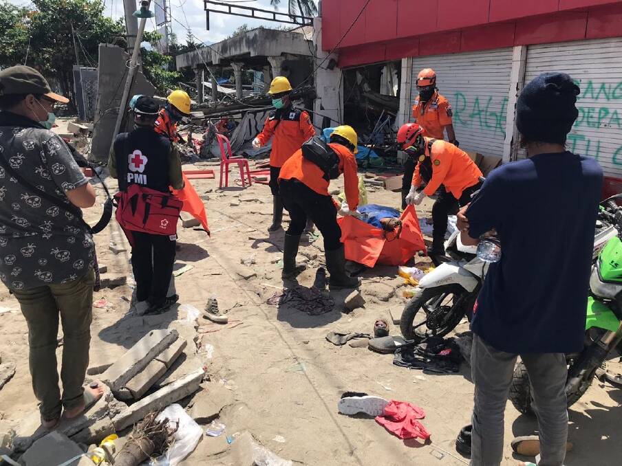 Volunteers retrieve a female body from the ruins of a shop in Talise, Palu, on Tuesday. Photo: James Massola