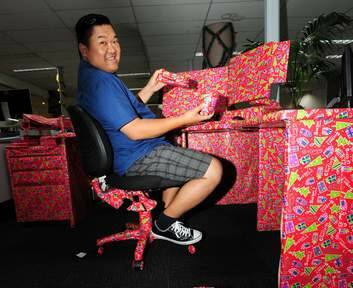 Canberra Times staffer Anderi Abdulhamid unwraps his Christmas prank - his entire workstation. Photo: Karleen Minney