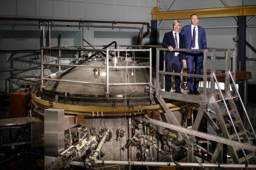 Director of the Australian Plasma Fusion Research Facility at ANU Dr Cormac Corr, right, standing with University of South China Professor Zhao Li Hong beside the 25 tonne H1 Heliac stellarator. Photo: Sitthixay Ditthavong