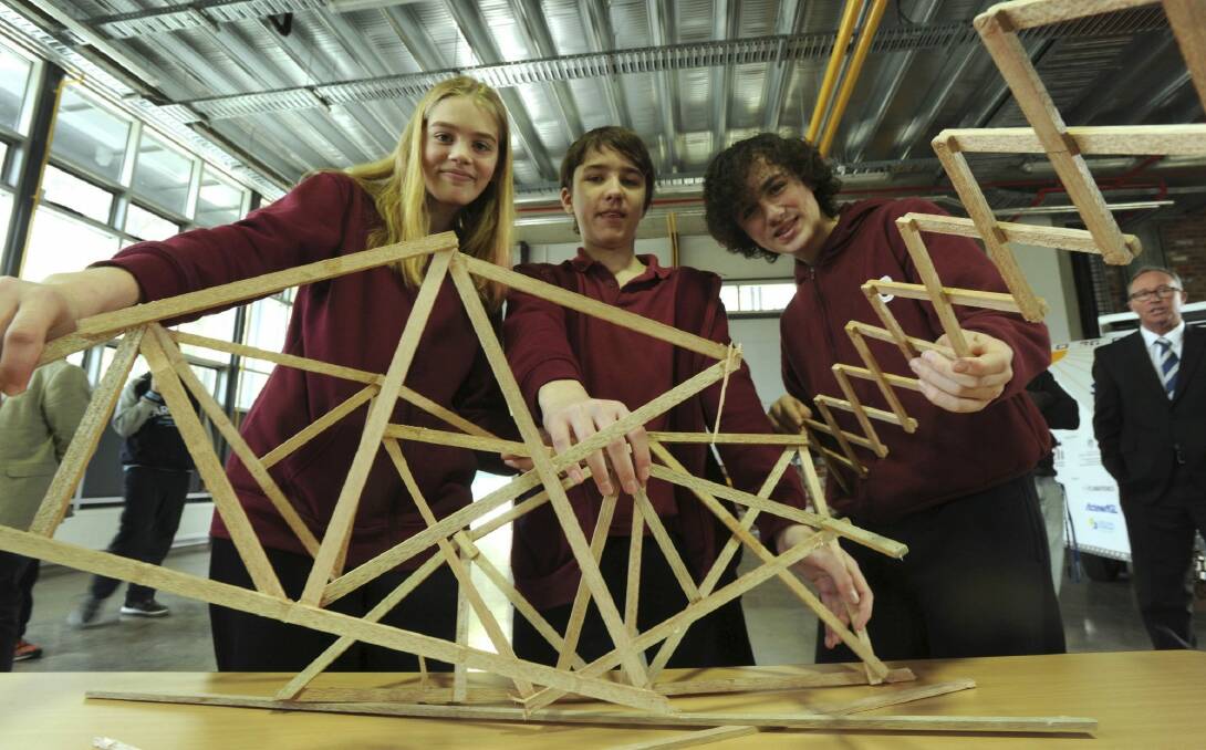 Namadgi School year 8 students Brianna Cather, Kiran Watkins-Molan and Shaun Payne with the remains of their 560-gram bridge, which took 112 kilograms of weight before snapping. Photo: Graham Tidy
