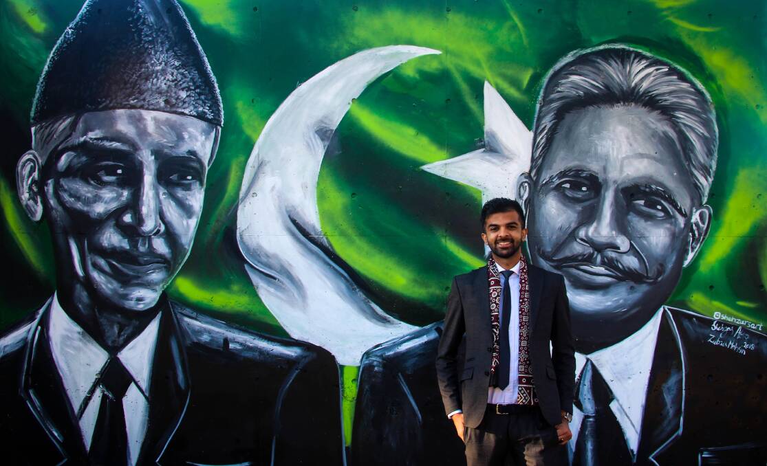 Artist Shehzar Abro alongside the mural he painted of Muhammad Ali Jinnah and Allama Iqbal on the façade of the Pakistan High Commission in Canberra. Photo: Supplied