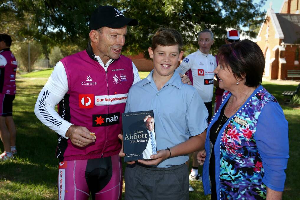 Tony Abbott hands out a copy of his book Battlelines during his Pollie Pedal fundraiser.  Photo: Alex Ellinghausen