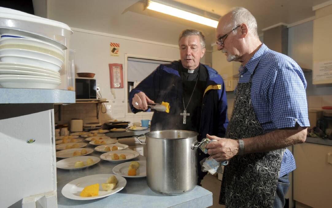 Catholic Archbishop of Canberra and Goulburn Christopher
Prowse helps to dish out meals at the St Vincent de Paul Society's ,
Samaritan House Men's Shelter at Hackett. Cook John Barr is in the
kitchen with him. Photo: Graham Tidy