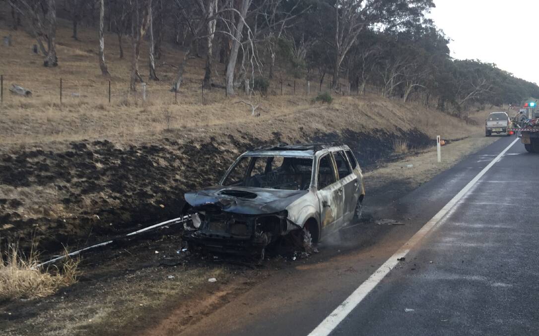 The burnt-out remains of a car that hit a kangaroo on the Monaro Highway near Michelago on Monday morning. Photo: Brent Wallis