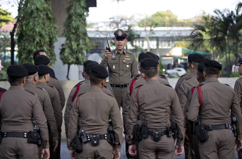 A police officer briefs others outside a polling station before the start of voting in Bangkok, Thailand, on Sunday. Photo: AP