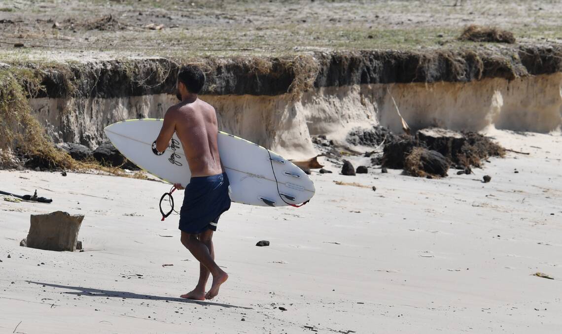 A surfer walks near beach erosion at Kirra on the Gold Coast on Saturday. Photo: AAP Image/ Darren England