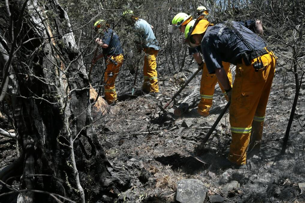 ACT Rural Fire Service and ACT Parks & Wildlife firefighters prepare a firebreak with hand tools. Photo: Jeffrey Chan