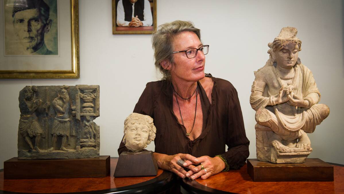 Romy Dingle looks at the Buddha who has been part of her life, together with the two other ancient objects from Pakistan which she returned. Photo: Elesa Kurtz.