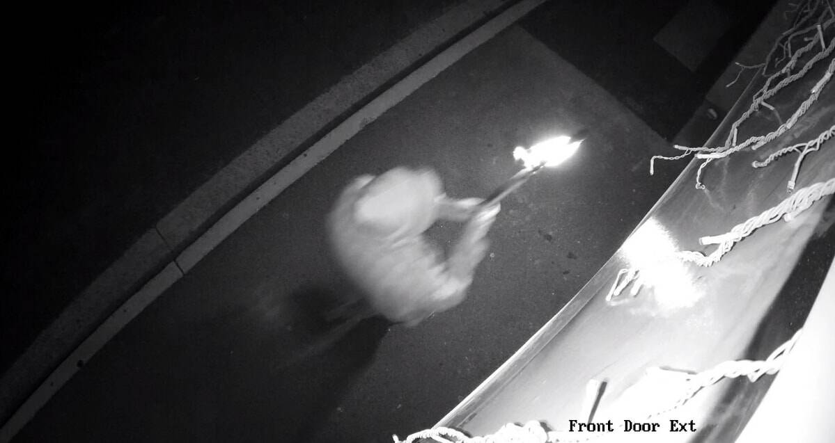 A person holds a flaming object, which was lobbed into Jenny Magic Massage in Phillip on Tuesday night. Photo: ACT Policing