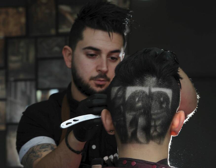 Belconnen barber Michael Daskalakis, owner of Boys 2 Men hair studio, has created Pokemon characters on the head of 18-year-old David Le, of Casey. Photo: Graham Tidy