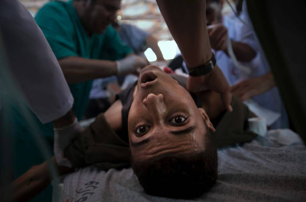 An injured Palestinian youth receives treatment in a field clinic after being shot by Israeli troops during a protest in the Gaza Strip in July. Photo: AP