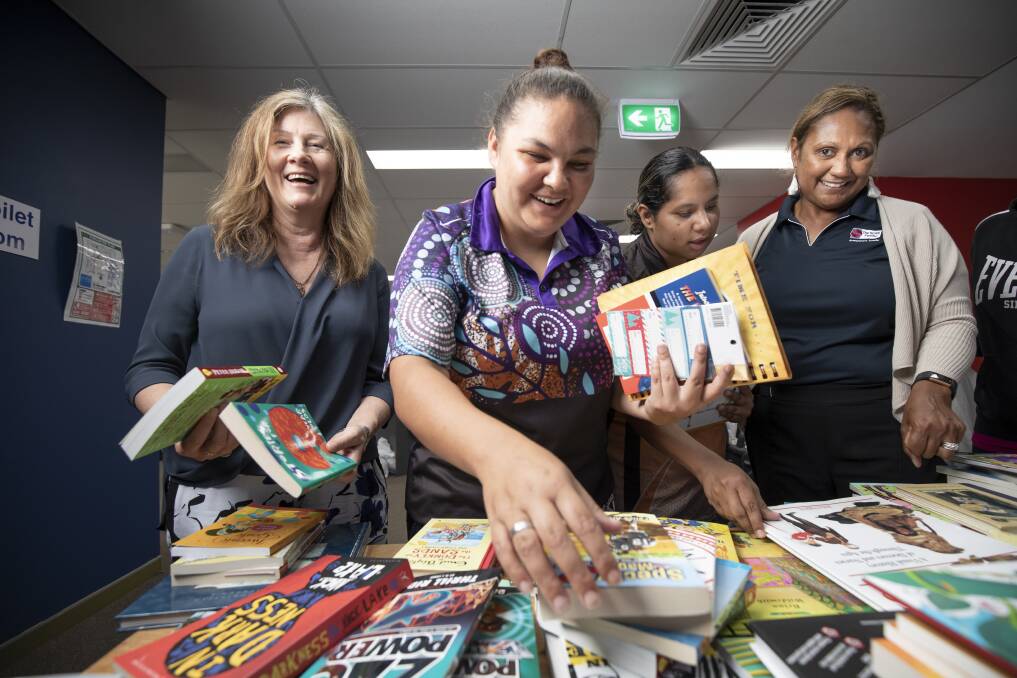 From left, The Smith Family office manager Robin Jarvis, Mikaila McEwan, Sarah Kennedy, and Smith Family program manager Karen Parter look through books at the Woden office on Thursday. Photo: Sitthixay Ditthavong