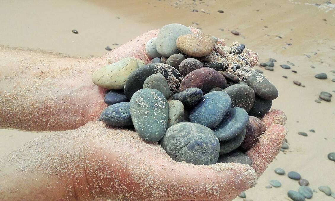 A handful of singing stones found buried beneath a metre of sand on Singing Stones Beach. Photo: Richard Fisher