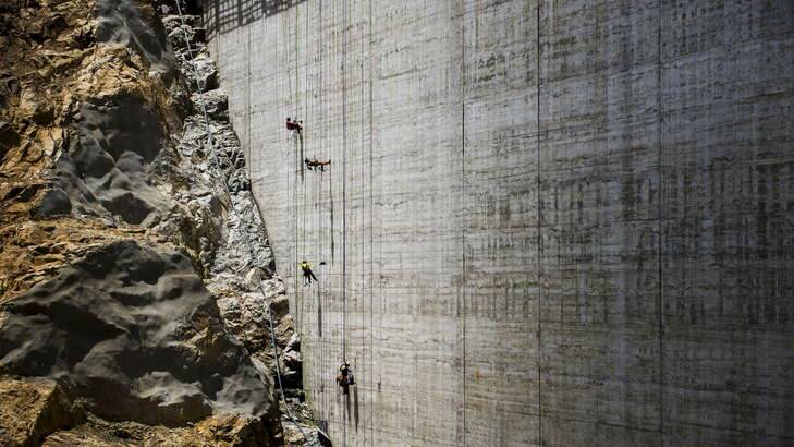 Absailing workers render the surface of the new Cotter Dam wall. Photo: Rohan Thomson