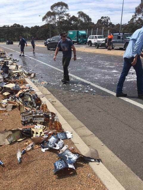 Other motorists stopped to help clean up the glass which was strewn for metres after a ute lost its load of beer on the Cotter Road. Photo: Supplied