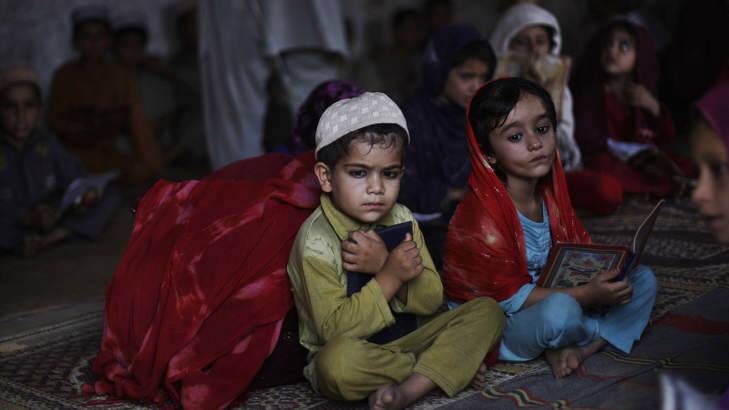 Afghan refugee Aisha Daoud, 4, right, and her brother Behrouz, hold a copy of the Quran while taking part in a daily class to learn how to read verses of the Quran at a mosque. Photo: AP