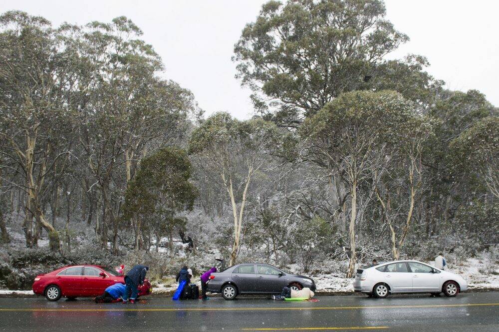 Motorists attach chains before proceeding to Perisher. Photo: Rohan Thomson