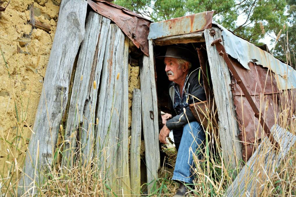 Peter Firth crawls out of the remains of "Ted's Hut" on the outskirts of Gundaroo. Photo: Tim the Yowie Man