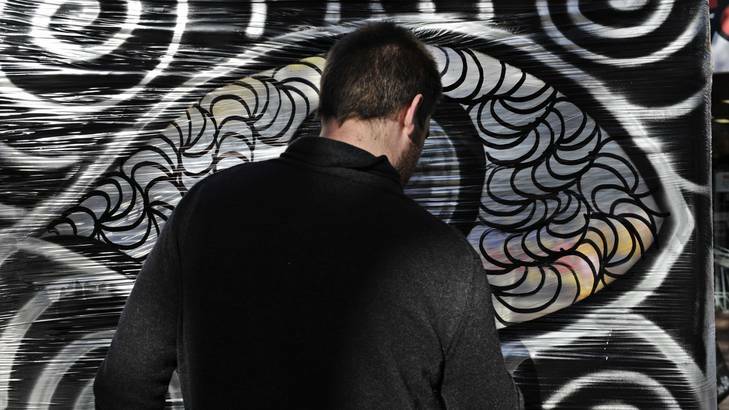 Street artist Chris Dalzell creates his own wall using Glad wrap then paints and draws on the plastic. Photo: Jay Cronan