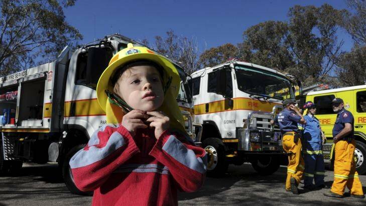 Ingo Wolf, 4, at the bushfire season launch. Behind him are two new ACT Rural Fire Service appliances, handed over at the ceremony. Photo: Graham Tidy
