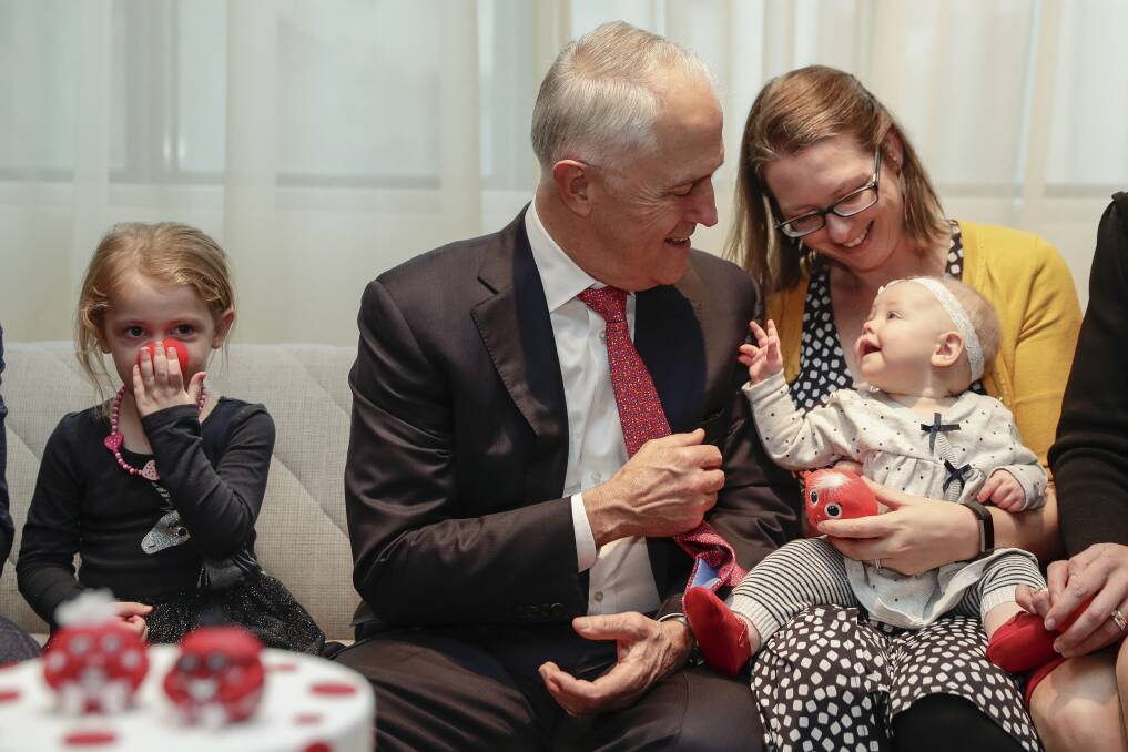 Prime Minister Malcolm Turnbull, with three-year-old Isobel Carroll and her mum Nicole Carroll and seven-month-old Elsie Carroll, celebrate the 30th anniversary of Red Nose Day at Parliament House. Photo: Alex Ellinghausen