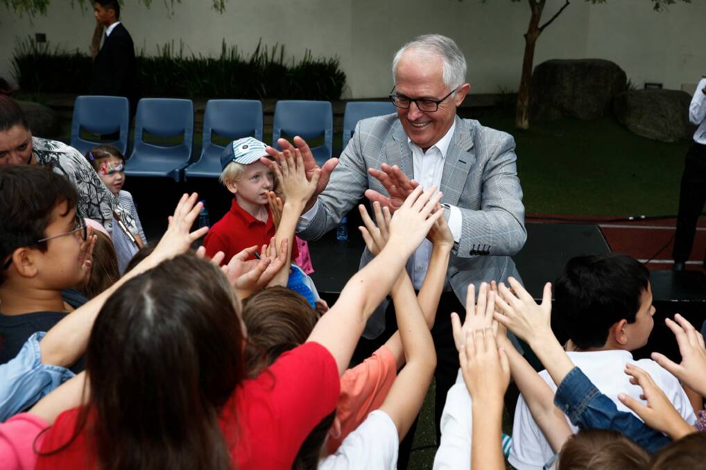 Prime Minister Malcolm Turnbull gives high-fives to children during his visit to the Australian International School in Hong Kong. Photo: FAIRFAX MEDIA POOL