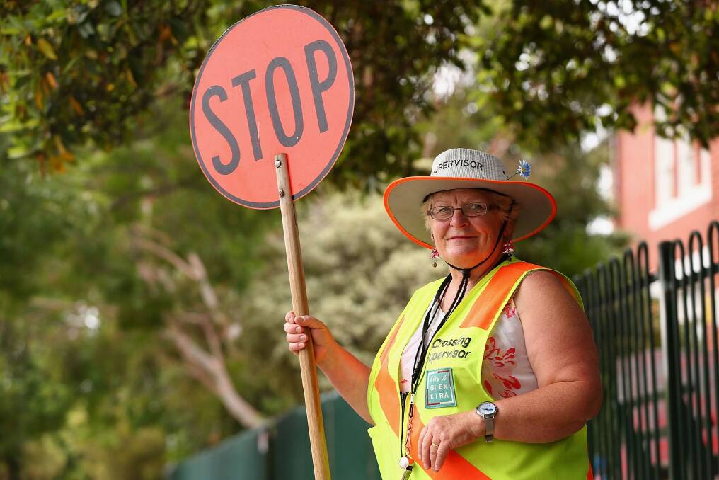 A school "lollipop" crossing supervisor in Melbourne. Labor says it will employ supervisors at 20 school crossings if re-elected. Photo: Robert Prezioso