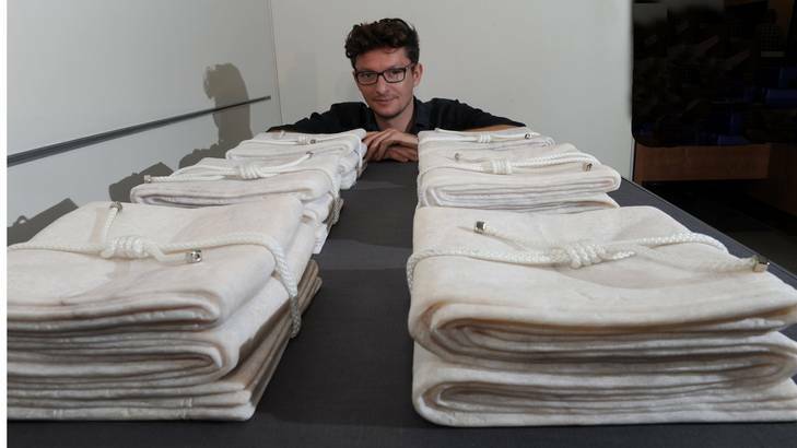Sculptor Alexander Seton with his work  <i>Six More</i>, a marble representation of six folded ceremonial flags, commemorating Australian soldiers killed in Afghanistan. Photo: Graham Tidy