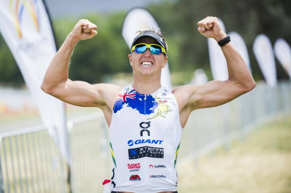 Winners are grinners: Ben Allen celebrates crossing the finish line as the winner of Canberra's inaugural T3X Endurance Triathlon on Sunday. Photo: Rohan Thomson