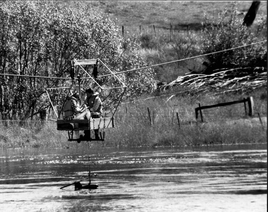 Workers from ACTEW check floodwater flow rates from a flying fox over the Molonglo River at Oaks Estate in 1989.  Photo: Darryl Gregory