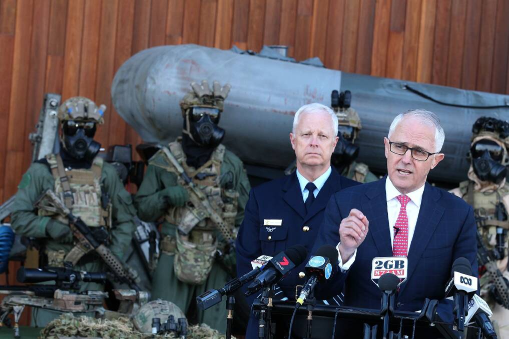 The Prime Minister backed by rows of gas-masked, camo-clad, machine-gun-toting special forces. Photo: Ben Rushton