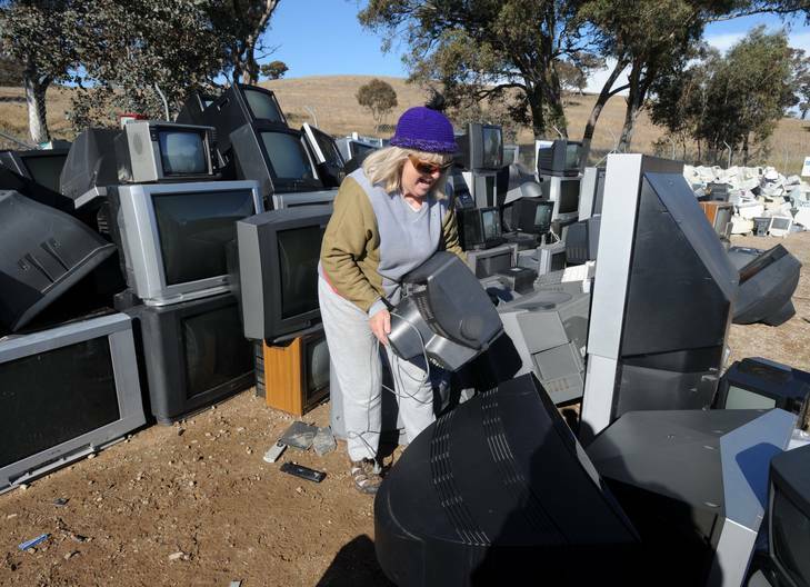 Dawn Richardson, of Curtin, places her old analog  television set  into the pile at the Mugga Lane tip. Photo: Richard Briggs