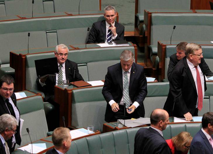 Independent MP Craig Thomson remains seated top as coalition and Andrew Wilkie, left, rise to vote to suspend him from the house. Photo: Andrew Meares