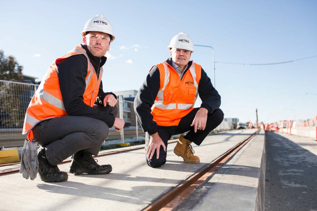 The test track slabs for the light rail have been laid. From left, Mark Jones deputy project director, and Glenn Stockton Canberra Metro CEO, next to the epoxy compound that encases the rail to both secure the rail in the track slot and as part of the stray current management system. Photo: Jamila Toderas