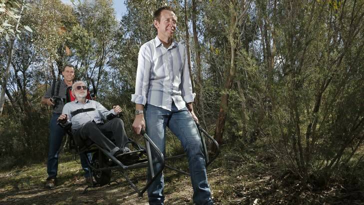 National Parks Association president Rod Griffiths(centre) gets some help testing out a new wheelchair from Peter Clarke from Lyneham and Shane Rattenbury MLA at the Tidbinbilla Nature Reserve. Photo: Jeffrey Chan
