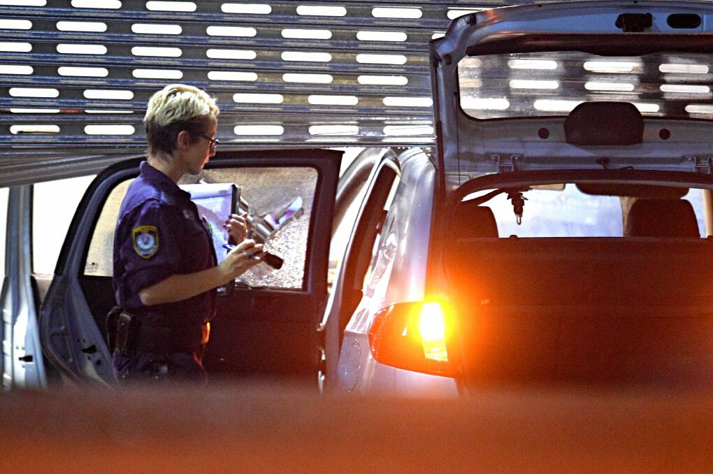 A police officer inspects a vehicle that crashed through the roller door of the Merrylands police station car park.  Photo: Sam Mooy