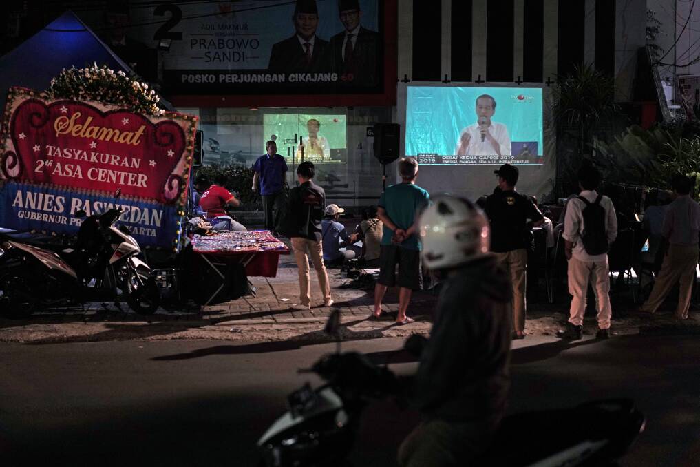 People watch last month's second presidential debate on the street in Jakarta. Photo: Bloomberg