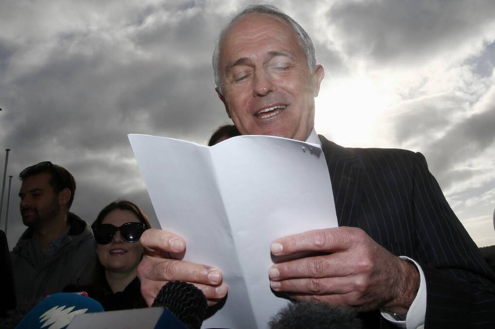 Prime Minister Malcolm Turnbull reads from a list of ALP spending pledges on Tuesday. Photo: Andrew Meares