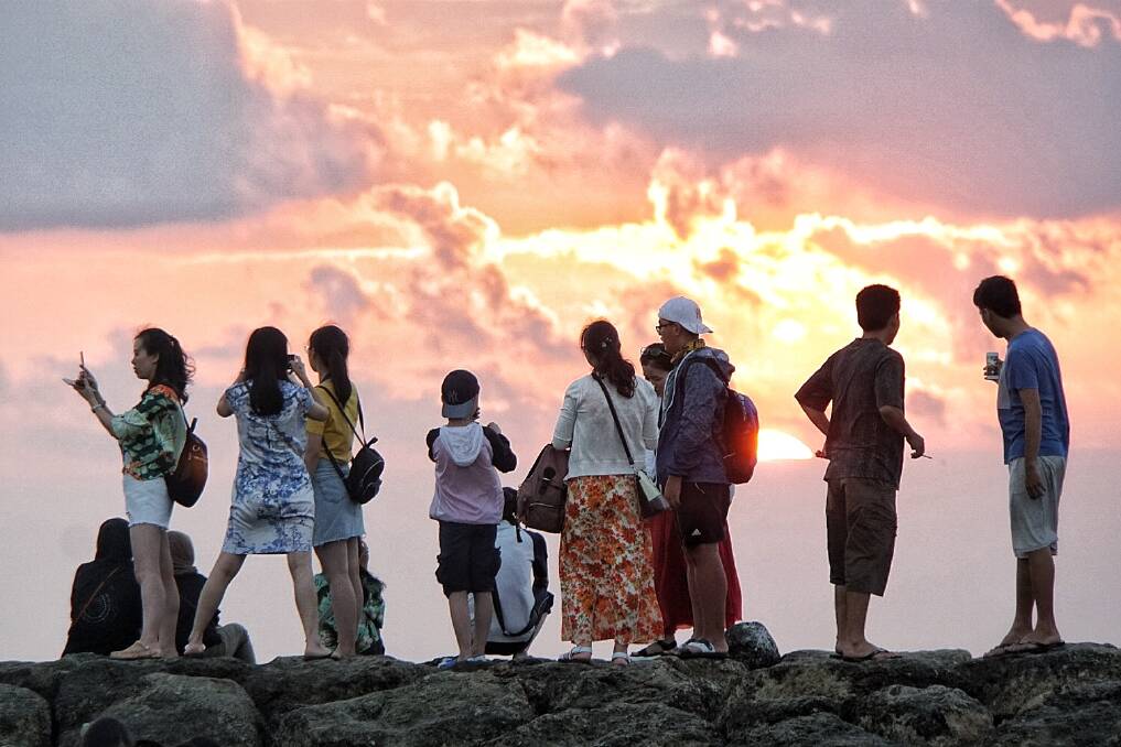 Chinese tourists watch the sunset on Kuta beach. Photo: Amilia Rosa