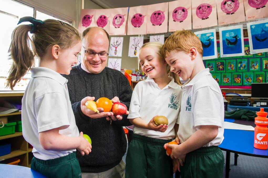 Farrer PS kindergarten students Elsa Connell, Grace Evans and Oliver Turnbull talk to Acting ACT Chief Health Officer Dr Andrew Pengilley about fruit while learning about good nutrition as part of a new school curriculum.  Photo: Rohan Thomson