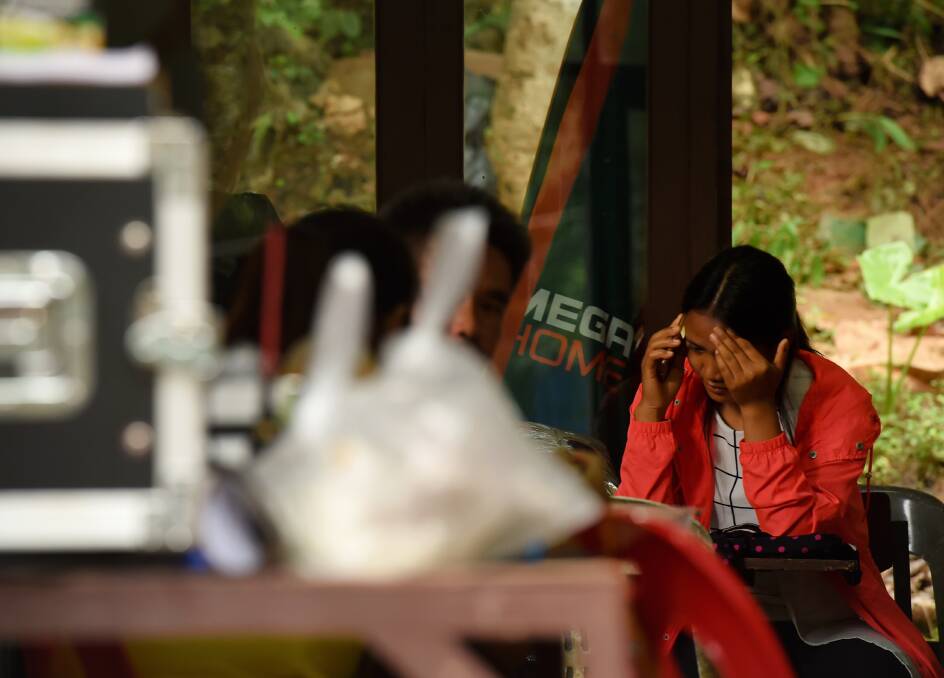 A relative reacts whilst taking a phone call at cave base camp on Saturday. Photo: Kate Geraghty