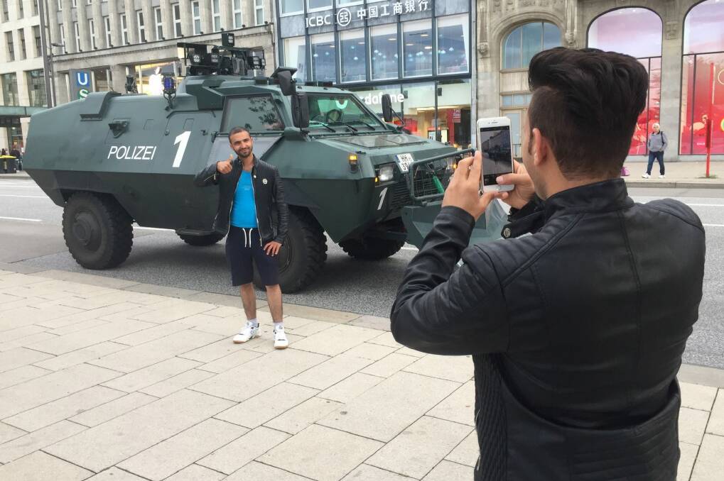 People take photos with police vehicles in Hamburg ahead of G20. Photo: Andrew Meares