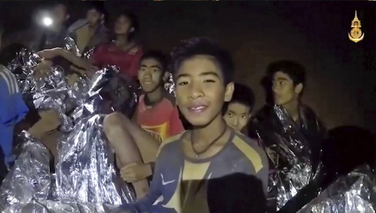 Thai boys smile as a Thai Navy SEAL medic helps the injured in the cave earlier in the week. Photo: Thai Navy/Facebook