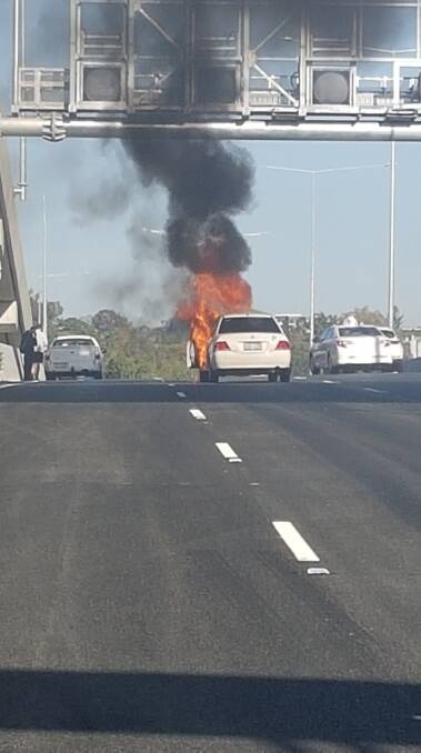 A car caught on fire follow a two-car crash on the Inner City Bypass. Photo: Melissa Anne