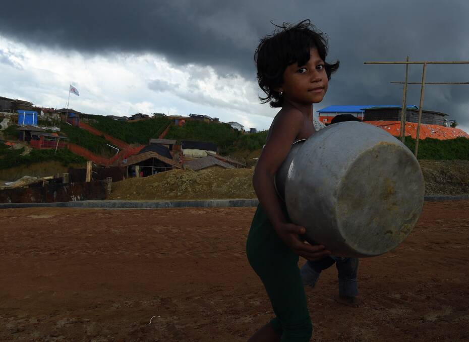 Storm clouds hang overhead as a Rohingya child carries a pot in Kutupalong camp. Photo: Kate Geraghty