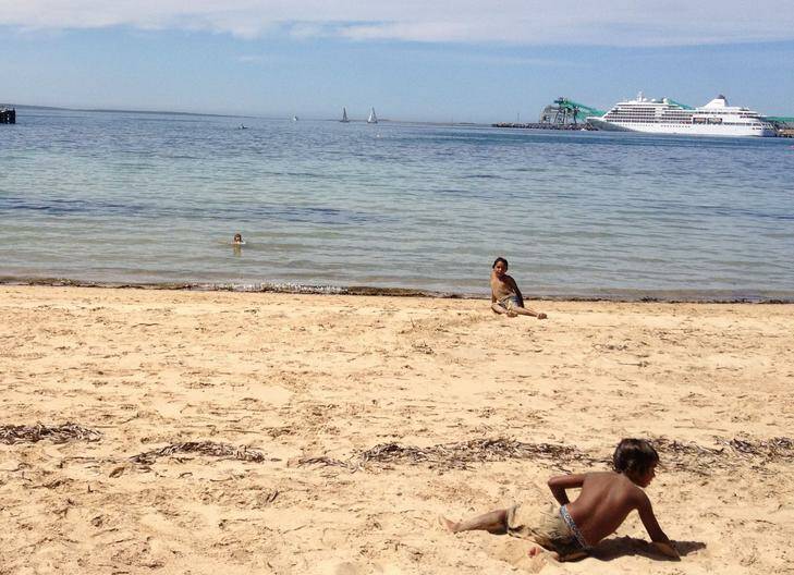 Aboriginal kids playing on the main beach at Port Lincoln with the super-luxury Silver Shadow in the background. Photo: Kirsten Lawson