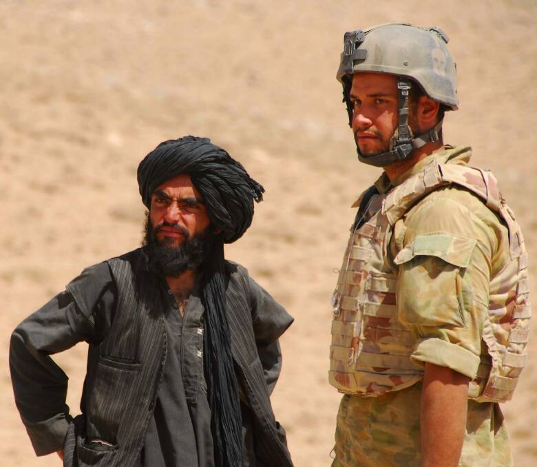 Jesse Bird (right) speaking to Afghan locals while conducting  identity checks in Afghanistan. Photo: Defence